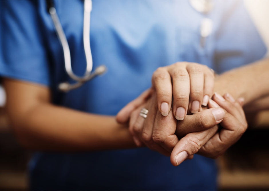 A nurse holds a patient's hand