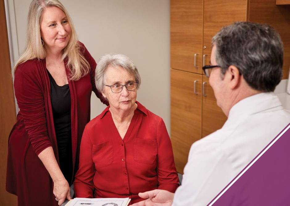 Older patient with younger caregiver consulting with a doctor